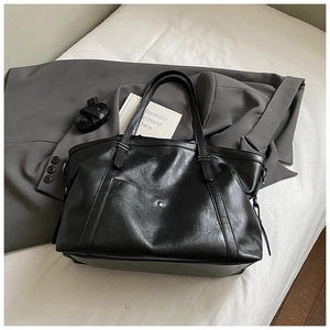 Détail du sac cabas en cuir mat noir avec boucle métallique et bandoulière amovible