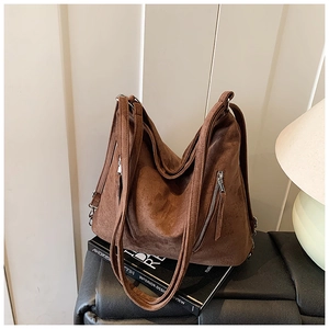 Gros plan détaillé d'un sac cabas en daim marron avec fermetures éclair argentées sur cuir