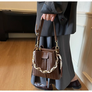 Detail of hand-woven dark brown bucket bag with silk scarf wrapped metal chain handle