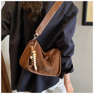 Nahaufnahme der braunen Wildledertasche mit Perlen und Metallelementen am Model