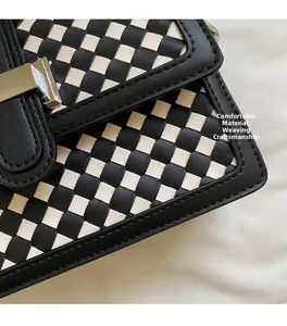 Detail of woven checkerboard leather texture with a silver square buckle on a shoulder bag