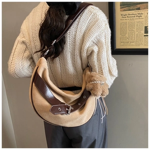 Detail of half-moon beige suede crossbody bag with leather straps and plush bear charm