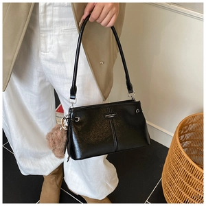 Détail du sac à bandoulière noir brillant avec logo en métal et breloque en peluche