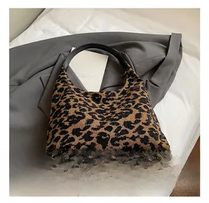 Detail view of leopard print hobo bag fabric with black leather handle on neutral background