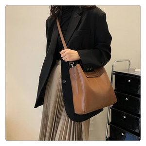 Brown leather tote bag featuring a unique hollow handle and slender shoulder strap