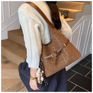 Detail of large brown leopard print shoulder bag with a cute plush bear charm on side