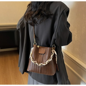 Detail of woven brown bucket bag with patterned silk scarf chain and leather strap