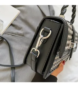 Detail shot of silver twist lock and woven texture on a black and white crossbody bag