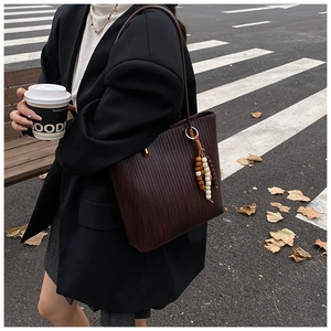 Borsa tote marrone testurizzata con ciondolo a perline indossata da una modella