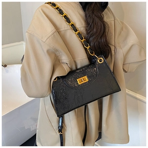 Close-up of black wrinkled patent leather bag with gold metal clasp and chain strap