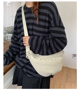 Close-up of a cream crescent crossbody bag showing its texture and strap detail