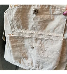Detail of durable snap button closure and layered pockets on beige textured nylon tote bag