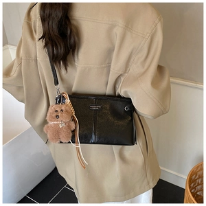 Détail d'un sac à bandoulière en cuir noir avec un joli pendentif en forme d'ours brun