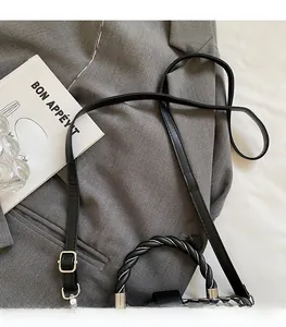 Detail of adjustable black leather strap and woven handle on checkered crossbody bag