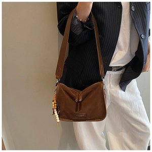 Detail einer braunen Wildleder-Bostontasche mit Doppelreißverschluss und Holzperlen