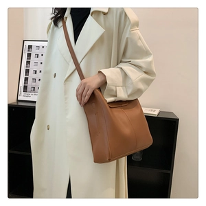 Detail view of caramel brown leather tote bag with vertical stitching and slim shoulder strap
