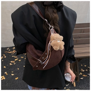 Detail of brown corduroy crescent bag with tassel and adjustable leather strap