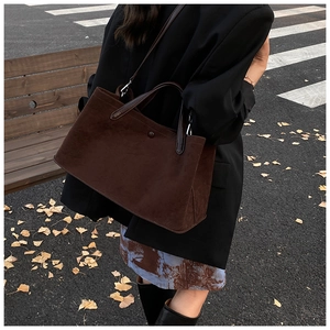 Close-up of deep brown suede tote bag with contrast leather handles in an autumn street setting