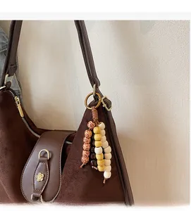 Gros plan du cabas en daim marron avec perles en bois et boucle fleurie dorée