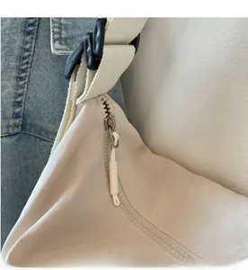 Close-up of smooth side zipper and adjustable woven strap on a beige nylon tote bag