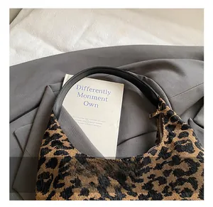 Detail of leopard print tote bag featuring woven texture and black leather handle