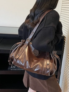 Dark brown high-shine leather tote bag with drawstring closure and wide shoulder strap