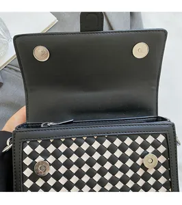 Detail view of woven leather bag showing secure magnetic snap button and interior zipper