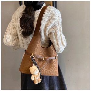 Detail of leopard print tote bag with brown straps and cute teddy bear fashion charm