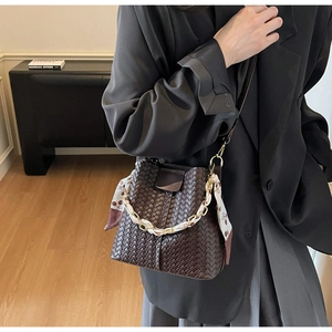 Detail of hand-woven bucket bag in dark brown with silk scarf handle and metal chain