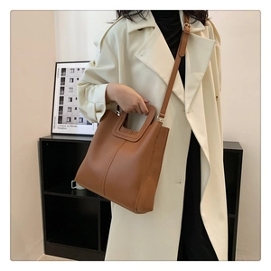 Fashionable caramel leather tote bag styled with a cream coat for a chic seasonal look