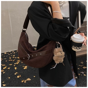 Detail of suede crescent shoulder bag with silver metallic hardware and bear charm pendant