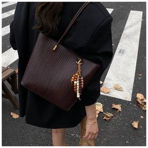 Dettaglio di una borsa tote intrecciata testa di moro con nappine di legno in stile autunnale