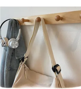 Close-up of cream canvas tote bag with adjustable black buckle and sturdy metal zipper