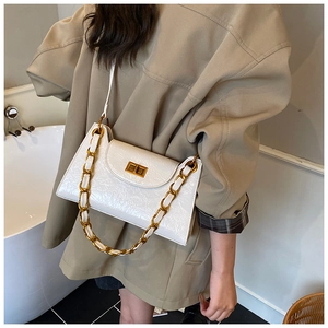 Detail of white crocodile texture crossbody bag with gold chain and turn-lock closure