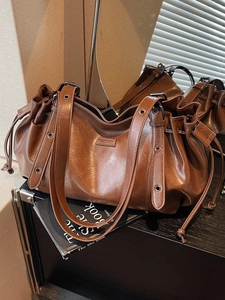 Brown glossy leather shoulder bag with drawstring and vintage metal grommets in large size