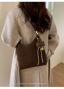 Detail of dark brown suede tote bag featuring a minimalist retro crescent design with charms