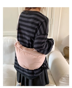 Detailed view of light pink crescent nylon crossbody bag worn in a casual lifestyle setting