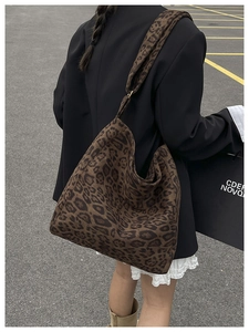 Outdoor street view of a large leopard print hobo tote bag with wide shoulder strap