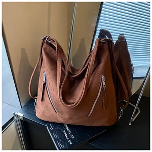 Détail du sac hobo en daim marron mat avec fermetures éclair argentées et grande capacité