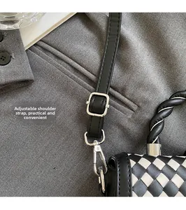 Detail of checkered woven bag showing adjustable black leather strap and silver buckle
