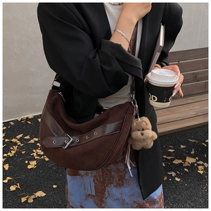 Detail of dark brown suede crescent bag with buckle strap and plush dog charm