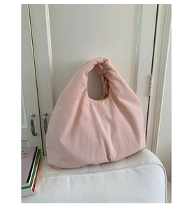 Detailed view of pink puffer tote bag with quilted texture on a white sofa setting