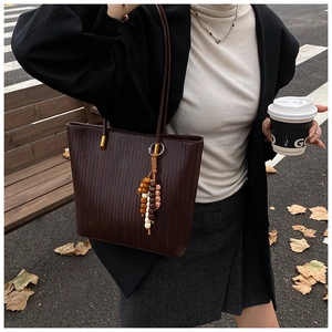 Dettaglio borsa tote marrone scuro con trama intrecciata e perline di legno decorative