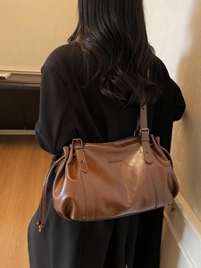 Retro brown leather shoulder bag with glossy texture and decorative metal buckles