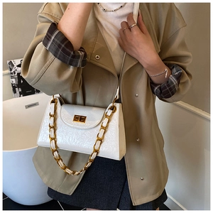 Detail of white crocodile texture bag with gold chain strap and metallic swivel lock