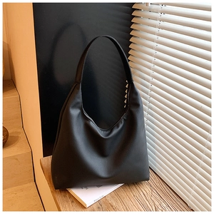 Sac fourre-tout minimaliste en cuir noir mat sur table en bois avec ombre élégante