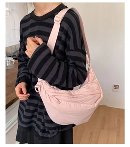 Detail of light pink nylon crescent bag with adjustable wide strap and zipper closure