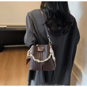 Detail view of woven leather texture on bucket bag with silk scarf handle and chain strap