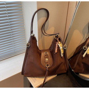 Detail of dark brown suede tote bag with vintage bead pendant and metal floral clasp