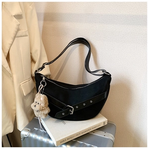 Detail of black crescent hobo bag with silver grommet straps and brown bear keychain